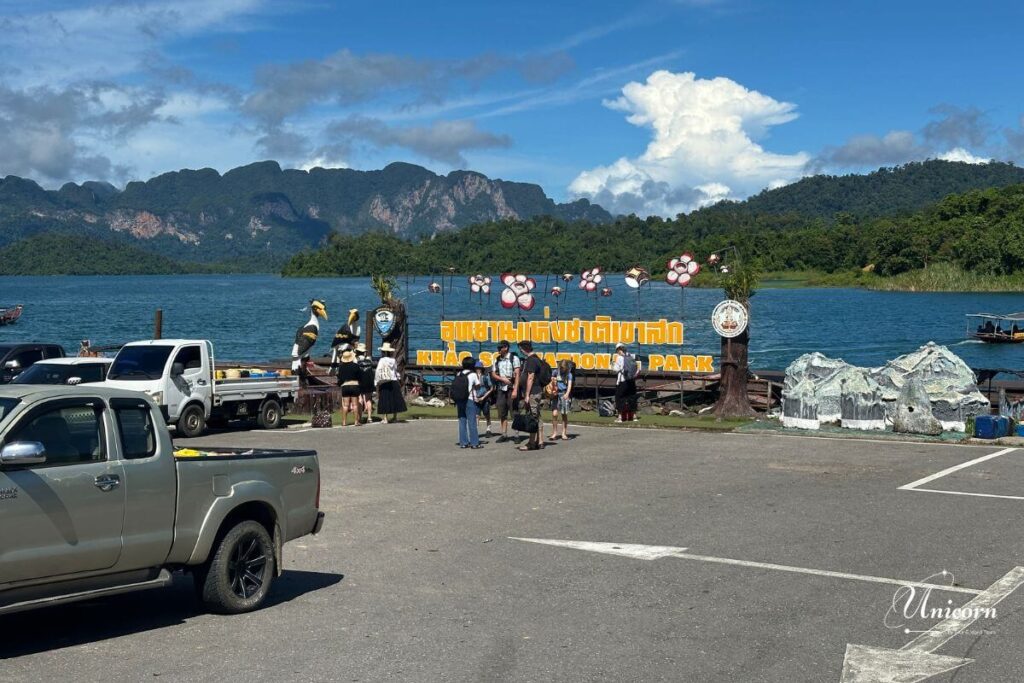 Private Transfer from Phuket to Cheow Lan Lake (Ratchaprapha Dam, Khao Sok) 4 Unicorn driver assisting travelers with luggage at Ratchaprapha Pier, gateway to Cheow Lan Lake.