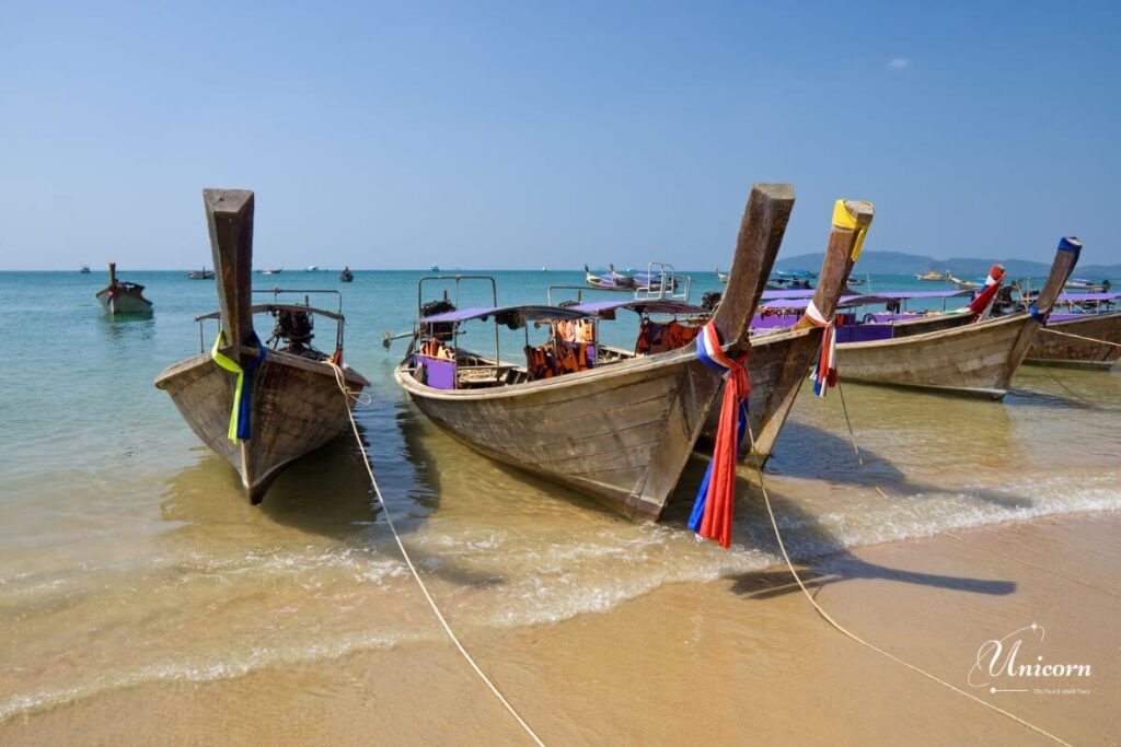 Private Transfer from Phuket to Ao Nang Beach – Fixed Price & Door-to-Door 4 Traditional long-tail boats anchored along Ao Nang Beach